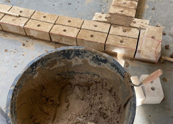 Mörtel im Kübel und Mauersteine werden vorbereitet.