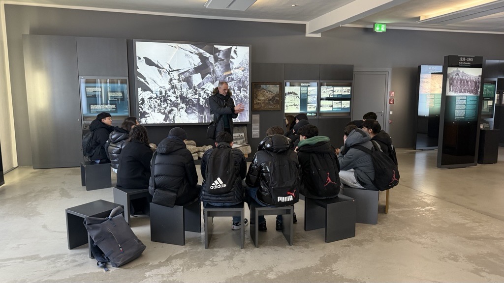 Eine Schülergruppe hört im Museumsbereich des KZ aufmerksam dem Dozenten zu. 