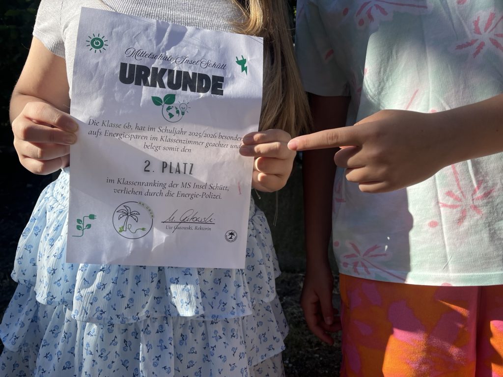 2 Schüler halten eine Urkunde in der Hand, die sie prämiert, da sie viel Energie gespart haben. 